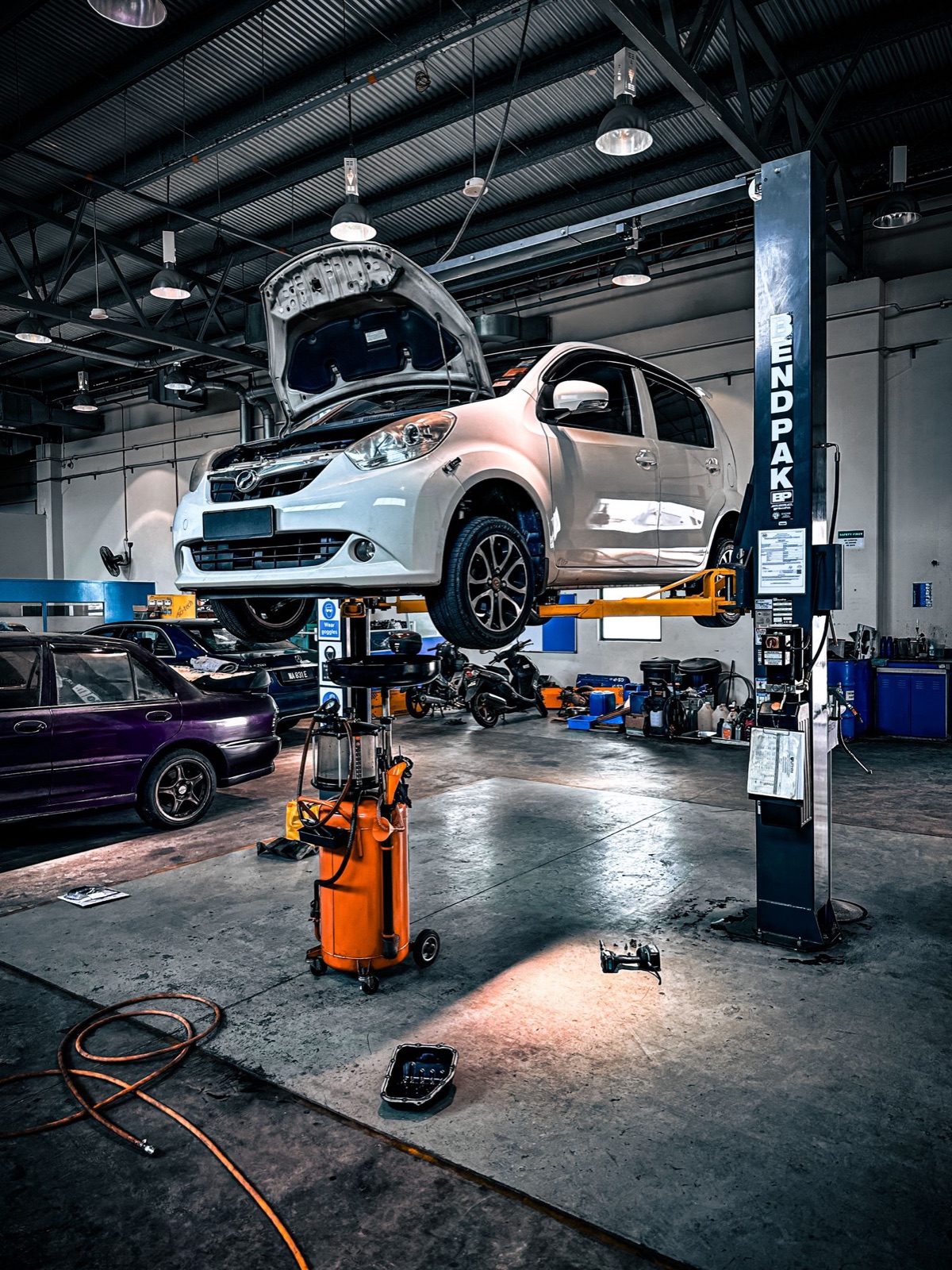 Row of blue two-post vehicle lifts in a service shop with cars raised